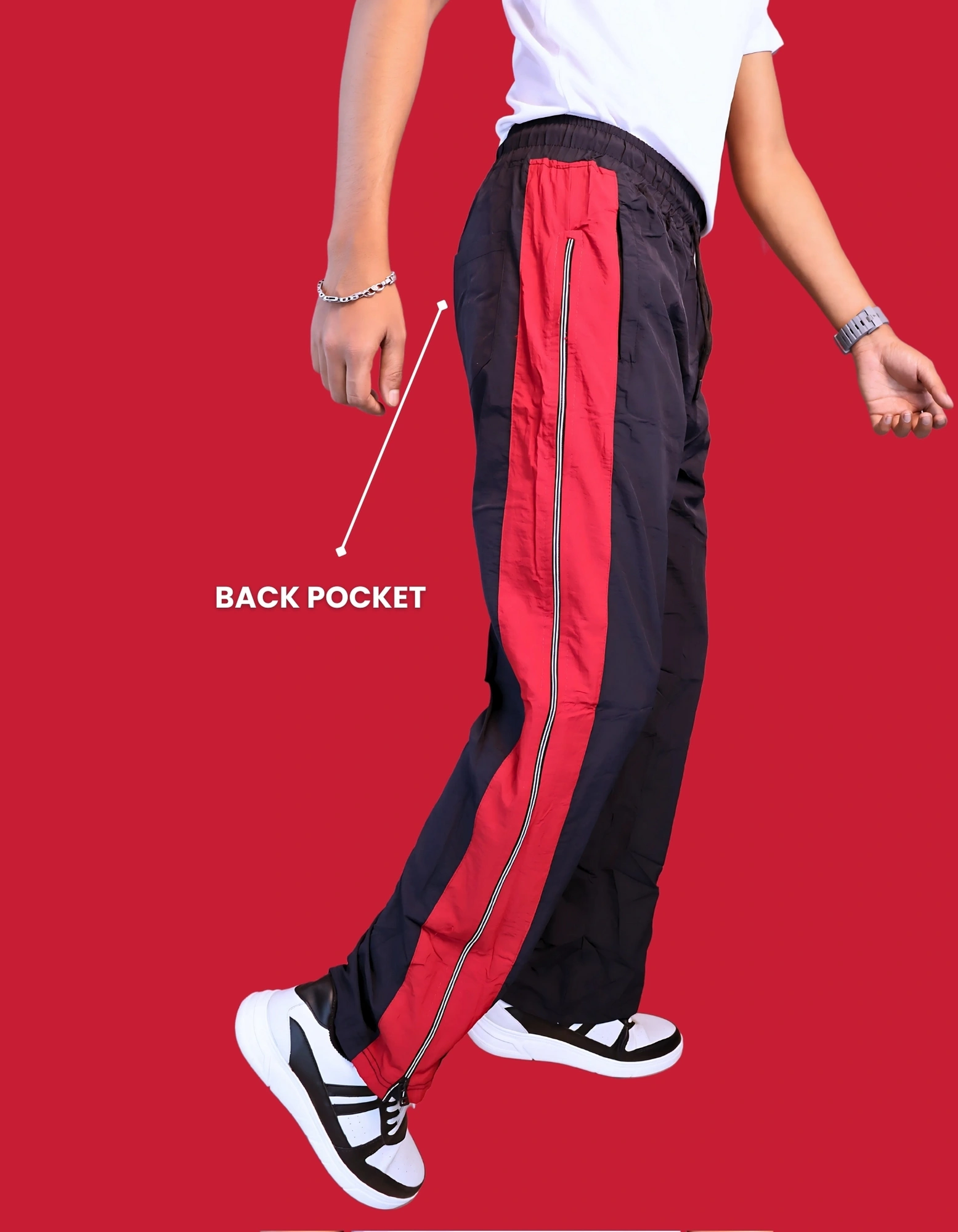"Full length view of men's red black white track pants with tapered fit and sneakers"